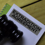 Extradition Agreement Document form and Black Judges gavel on wooden desk. Law concept